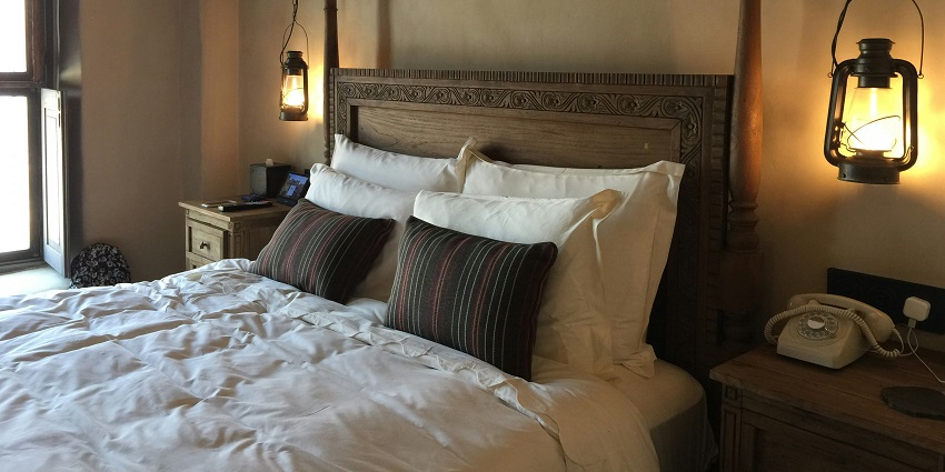 Cosy hotel room with a neatly made bed, warm lighting, and simple furnishings.