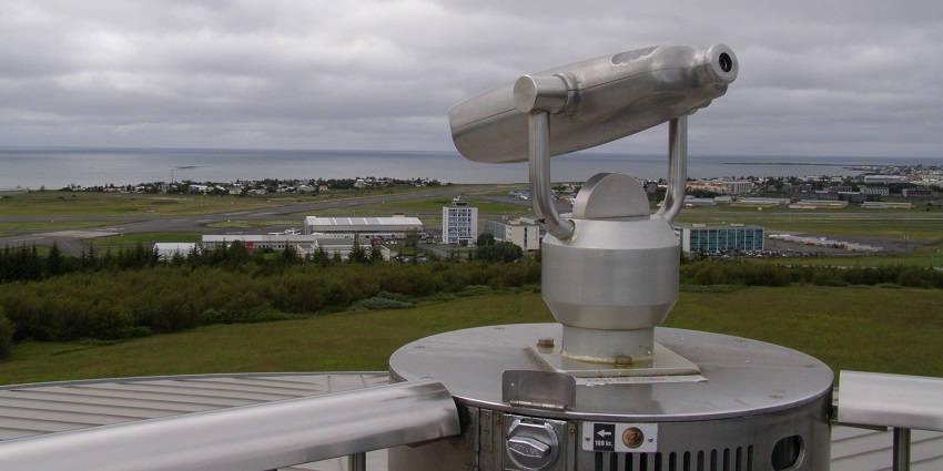 A view of Perlan, an iconic dome glowing under clear skies, with the surrounding nature nearby.