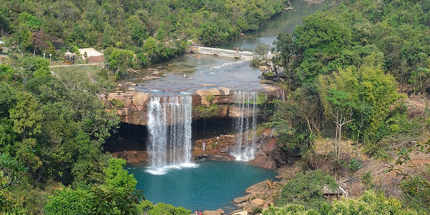 Waterfalls in Meghalaya with water falling in the small water body and distant people.