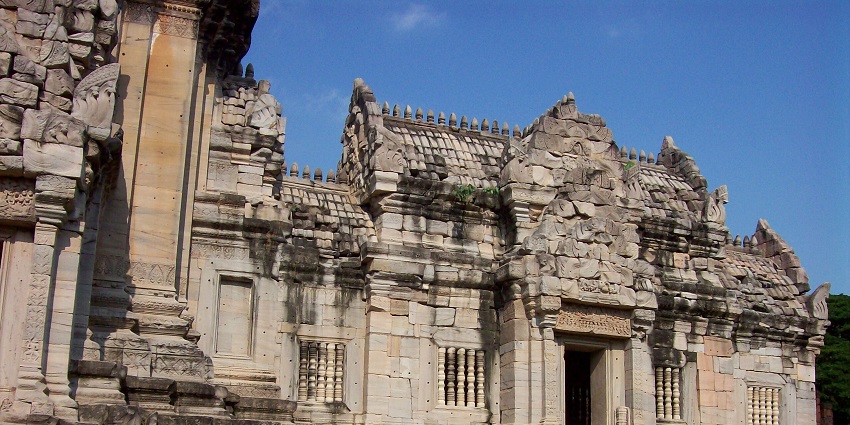 An image of ancient temple ruins with a central stone tower at the Phimai Historical Park.