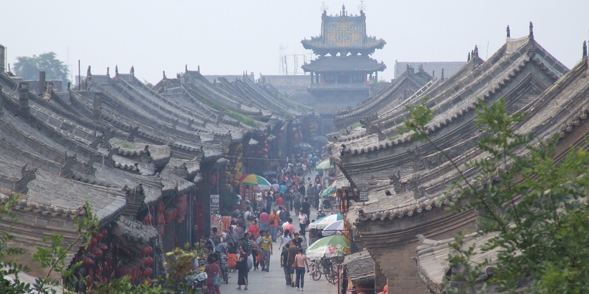 Street of Pingyao ancient city with unique roofs of the houses and people on the street