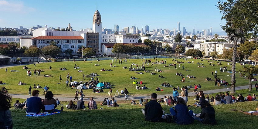 People relaxing at Dolores Park with a view of the San Francisco skyline, highlighting is San Francisco worth visiting.