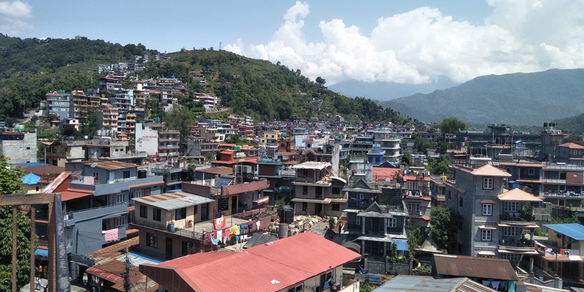 Colourful houses in Pokhara, Nepal nestled against lush hills under a bright blue sky