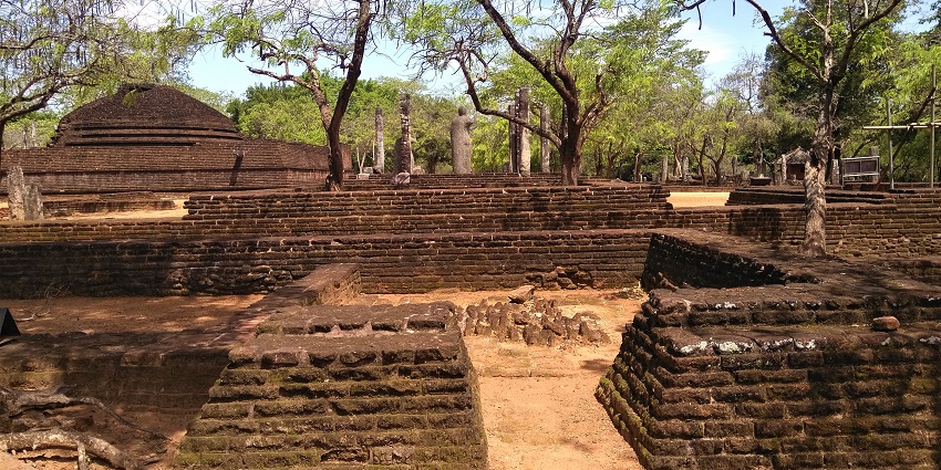 Ancient ruins of the Kingdom of Polonnaruwa in Sri Lanka with stone structures surrounded by green trees and clear skies.