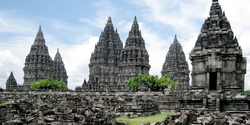 Ancient Hindu temple towers at Prambanan, one of the most iconic monuments in Indonesia, rise against a partly cloudy sky.