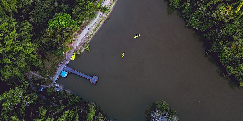 Minaki Dam is surrounded by dense greenery in Pugu Hills Forest Reserve, reflecting cloudy skies in its calm, serene waters.
