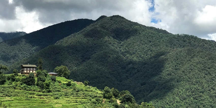 Punakha region in Bhutan with a distant building among the green trees and mountains, one of the places to visit in Bhutan in August.