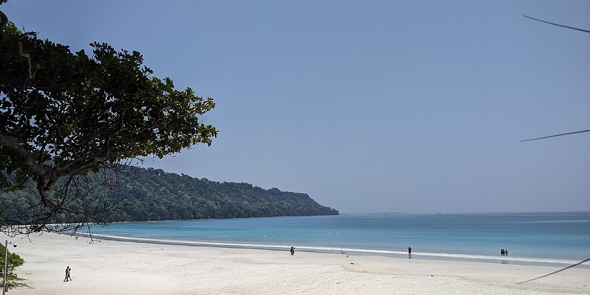 Visitors enjoying the scenic Radhanagar Beach, with white sands and turquoise waters