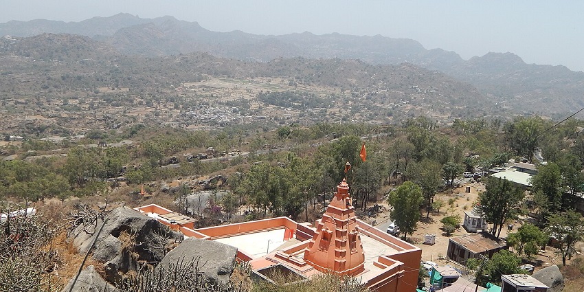 Temple at Mount Abu from above with traditional Hindu architecture and distant vehicles.