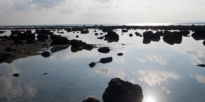 Ramnagar Beach, Andaman view with scattered stones along the shore under a clear sky.
