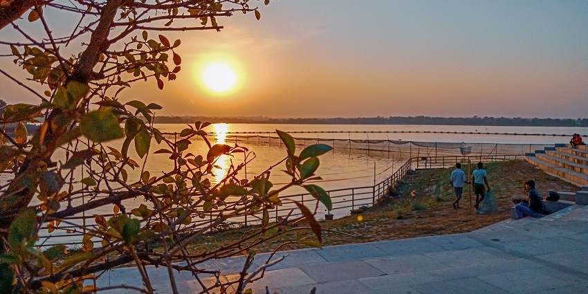 Scenic lakeside park with trees, pathways, gazebos, and a view of calm blue water.