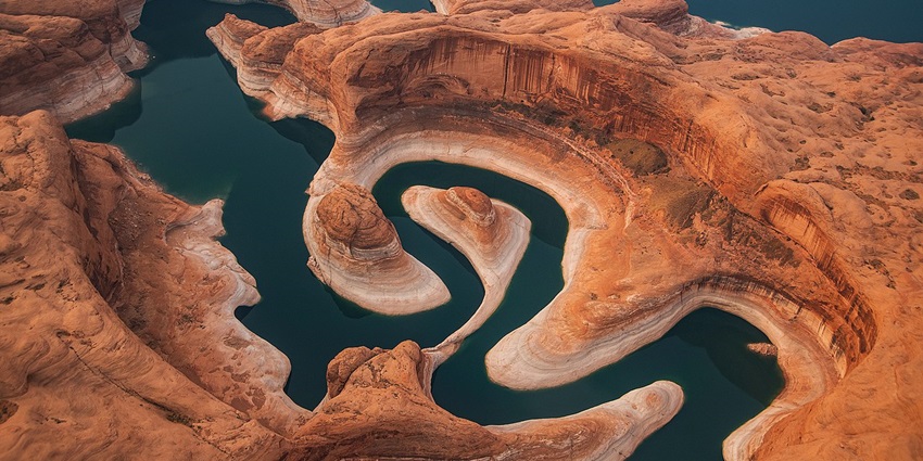 Reflection Canyon with a unique still water body surrounded by red stone, small mountains, one of the best hidden places in Utah.