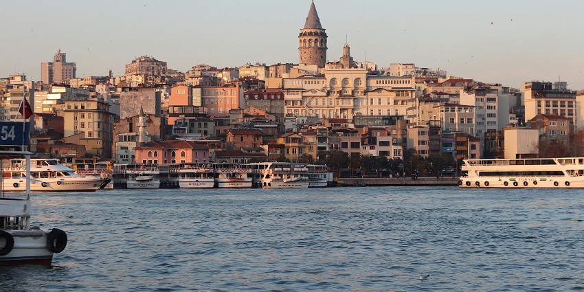 Scenic cityscape near a calm body of water with boats, buildings, and clear skies.