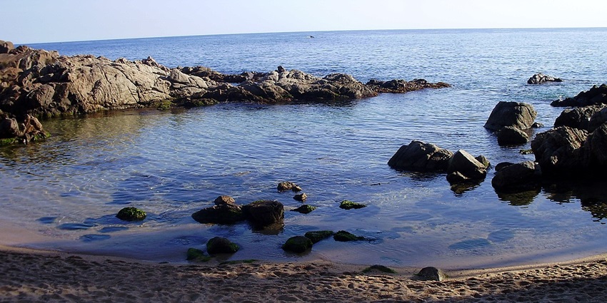 Visiting the crystal-clear waters and rocky coves at the tranquil, hidden beach of Cala Estret, one of the top things to do in Costa Brava.