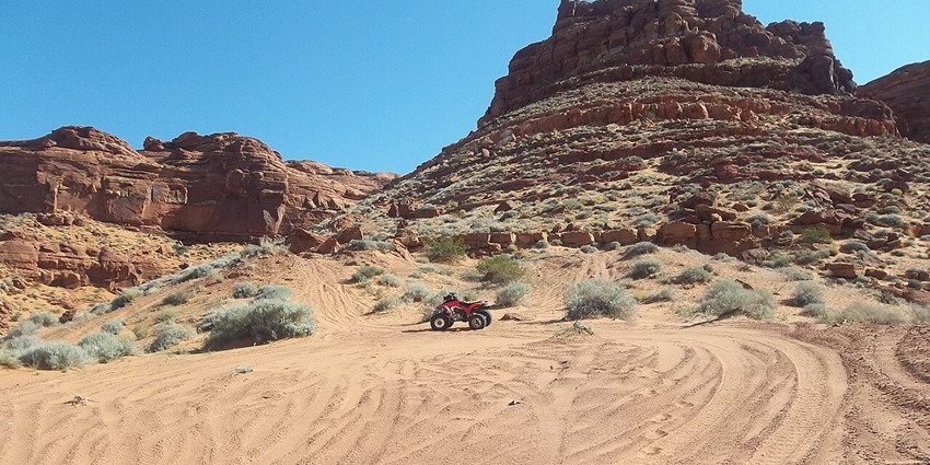 Thrill-seekers kick up red sand while navigating rolling dunes on an ATV in Sand Hollow State Park.