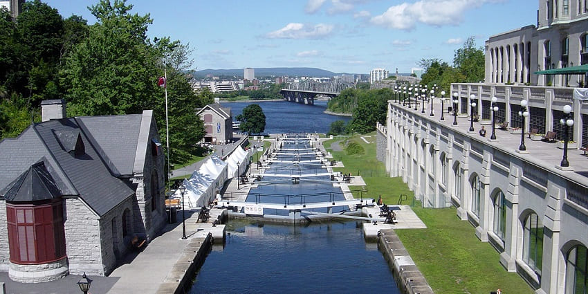 Rideau Canal with water flowing into a large water body and buildings on both sides