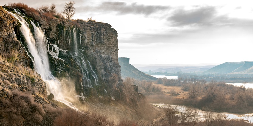 Ritter Island in Thousand Springs State Park with waterfalls flowing from rocky hill.