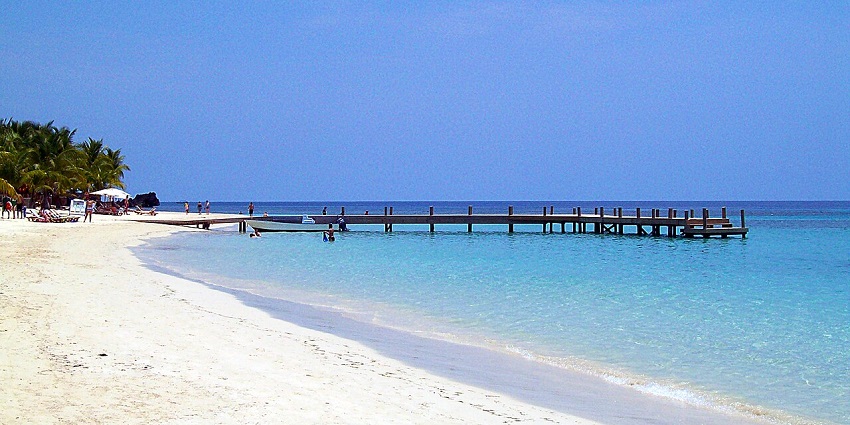 A pristine white sand beach with turquoise waters in Roatán, a top place to visit in Honduras.