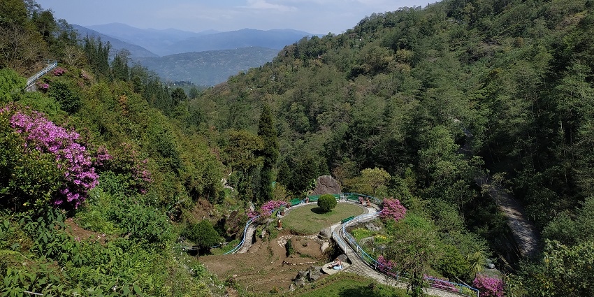 Rock garden from the highest steps of the park with a trail, railings on both sides and greenery, one of the places to visit in Darjeeling in June.