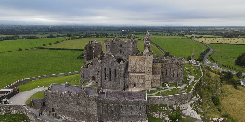 Panoramic view of Rock of Cashel ruins overlooking green fields under a clear sky