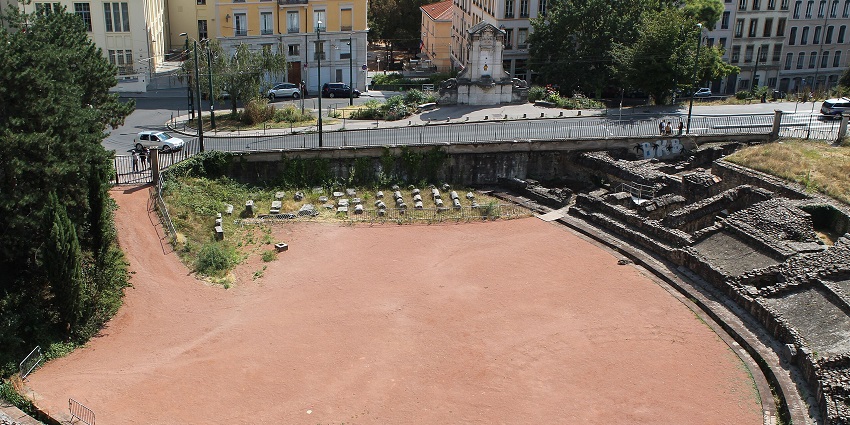 Roman Amphitheatre of the Three Gauls with ruined architecture, broken walls and vehicles parked on the street