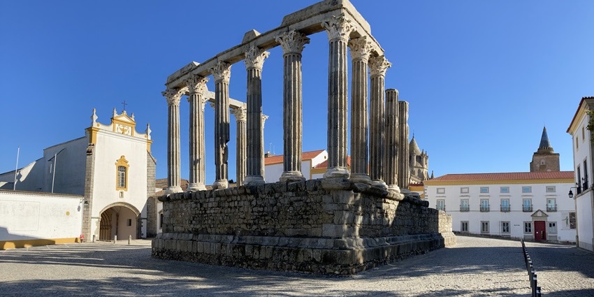 Corinthian columns of the Roman Temple of Évora against a clear sky.