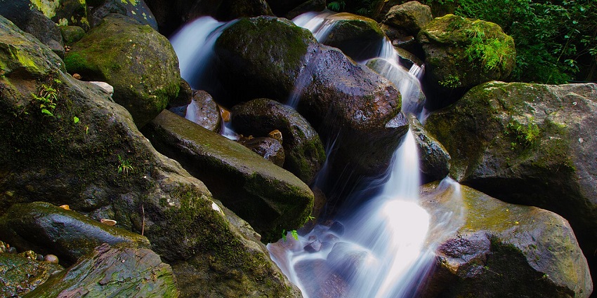 Waterfall in Meghalaya with water flowing on the rocky surface and moss on the rocks.