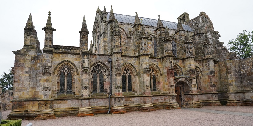 Exterior view of Rosslyn Chapel showcasing its detailed Gothic stone carvings and spires.