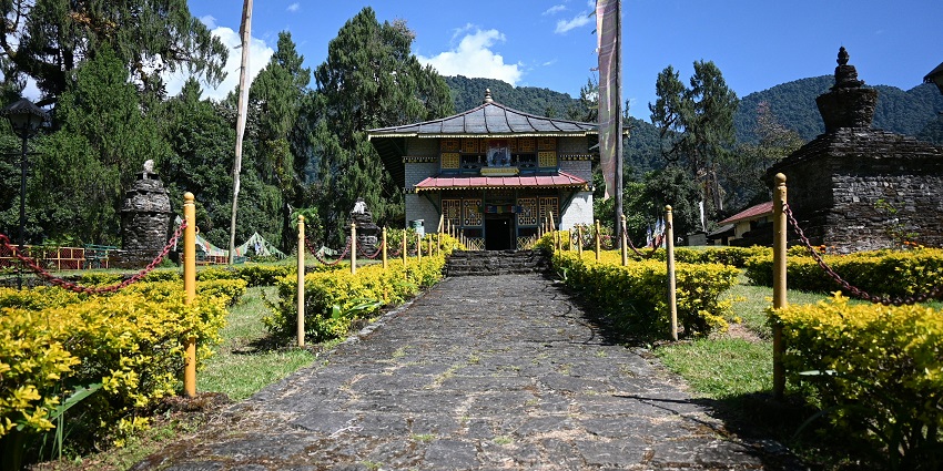 An image of Sa-Ngor-Chotshog Centre with traditional architecture, surrounded by lush greenery and mountains.