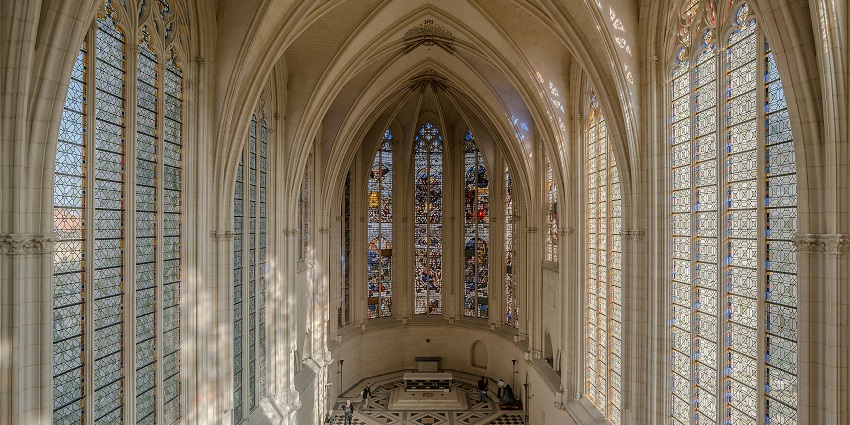 The interior of the chapel with tall, intricate stained glass windows and a vaulted ceiling, one of the most stunning historical places in France.