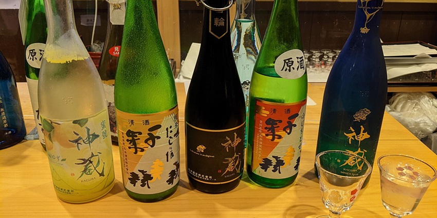 Rows of traditional sake bottles with Japanese labels on a wooden shelf—classic things to buy in Tokyo.