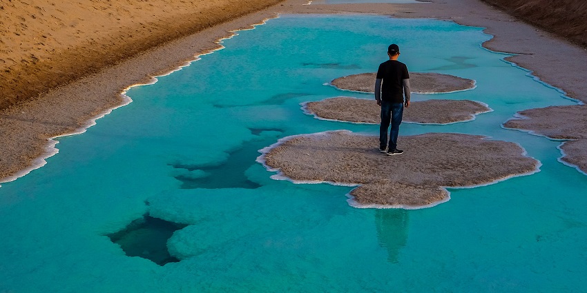 A person standing in the middle of a stunningly mesmerising lake that is also known as the Salt Lake.