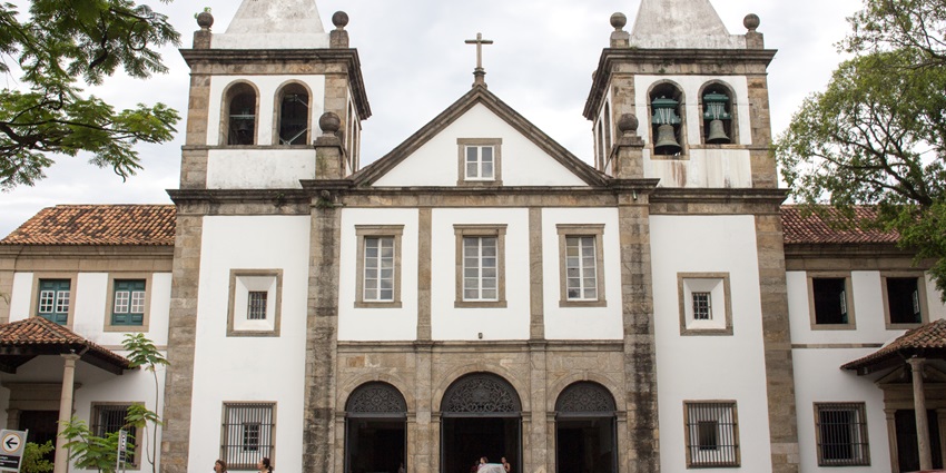 Historic white church with twin bell towers, arches, and stone details on a cloudy day.
