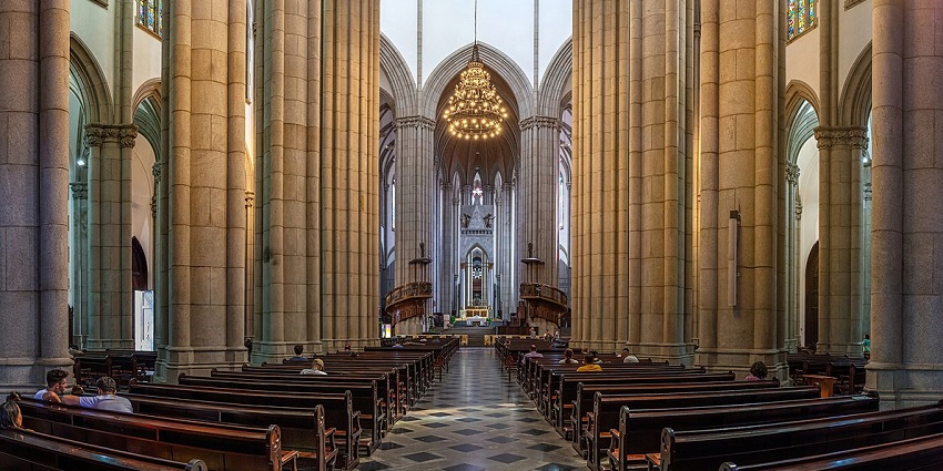 The grand facade of São Paulo Cathedral, with Neo-Gothic architecture and tall palm trees.