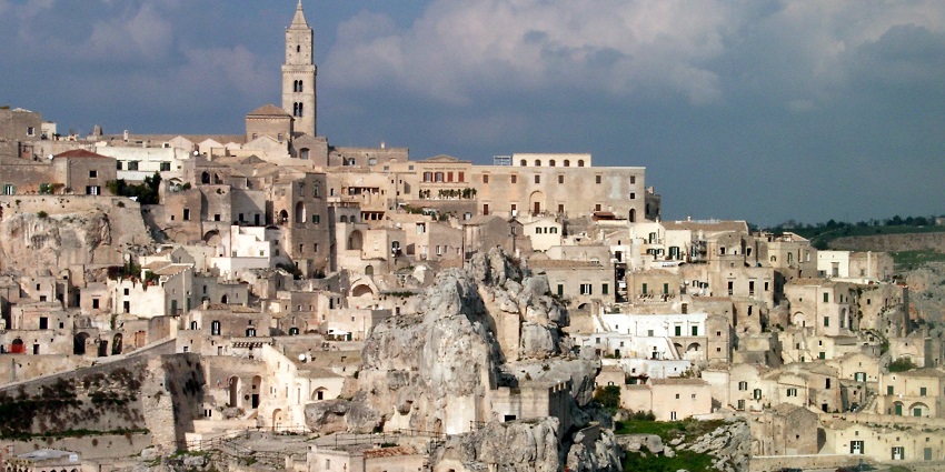 Sassi di Matera with multiple traditional Italian architectural buildings and a distant church