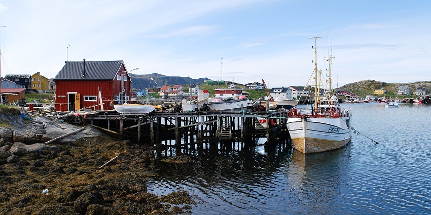 A picturesque view of an exotic fishing village by the side of a water body beneath a clear sky.