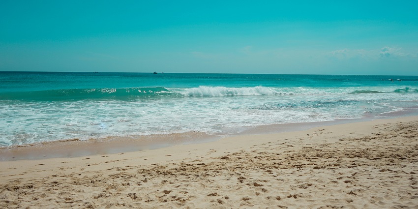 Seminyak Beach, with sandy shore and crystal clear water under a clear sky.