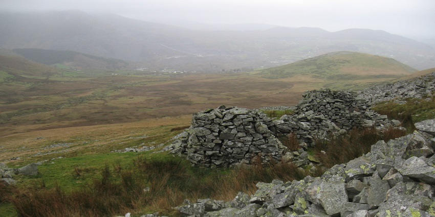 A deserted quarry located in the middle of greenery on a gloomy day, with hills in the backdrop.
