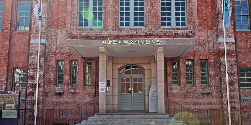 Entrance gate of Old Seodaemun Prison History Hall with two flags and a Korean sign