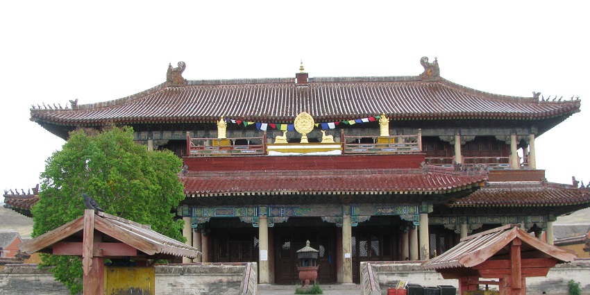 Monastery in Mongolia with traditional Buddhist architecture, flags and stairs on the entrance