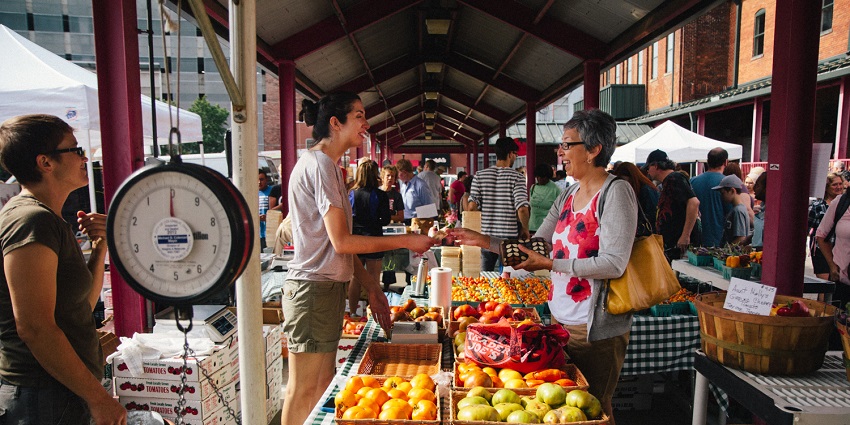 View of fresh produce, flowers, and vendors selling goods, creating a outdoor shopping scene.