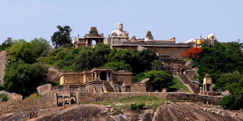 Massive stone statue on a hilltop with steps, surrounded by rocky terrain, amongst the best places to visit in Kanataka in February.