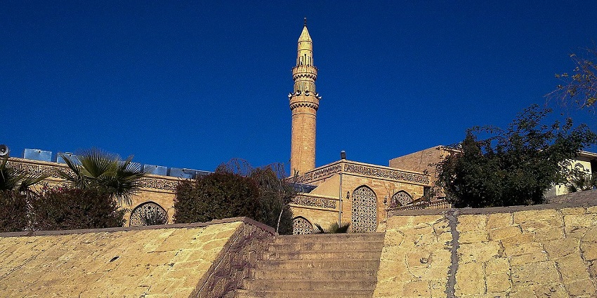 Shrine of prophet Yunus with a tall minaret, traditional Islamic architecture and green trees