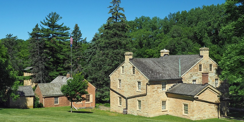 Sibley historic site with multiple traditional architectural buildings and a tall United States flag