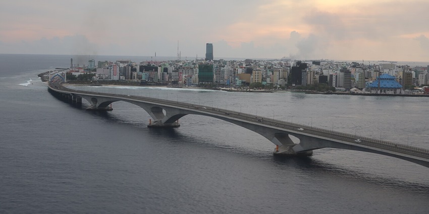 The Sinamalé Bridge from above with vehicles on the bridge, distant buildings and road lights