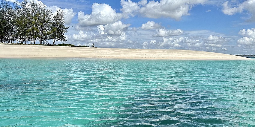 Pristine shore of Sinda Island with clear blue waters and white sandy beach, making it one of the best places to visit near Dar es Salaam.
