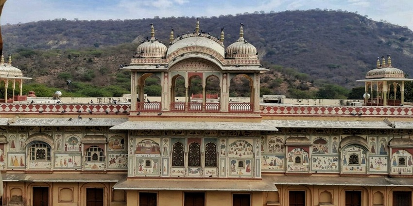 Mughal-style garden in Jaipur with floral beds, pavilions, and wall frescoes amid Aravalli hills, among the top places to visit in Jaipur in August.