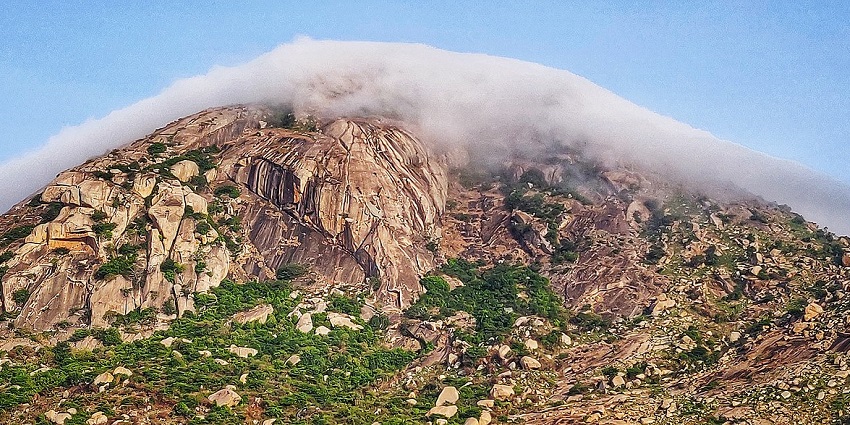A dramatic cloud hovers above the Skandagiri hills, casting shadows over the distant rolling terrain.