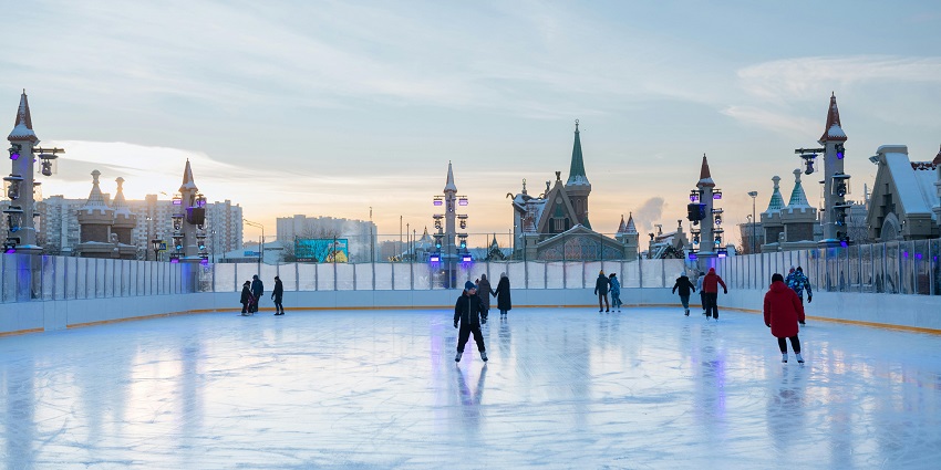 Skaters enjoying winter fun under lights at a scenic outdoor rink in downtown Edmonton.