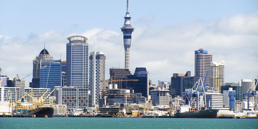 A towering view of Auckland's Sky Tower rising above city buildings and clouds, highlighting one of the most iconic modern monuments in New Zealand.